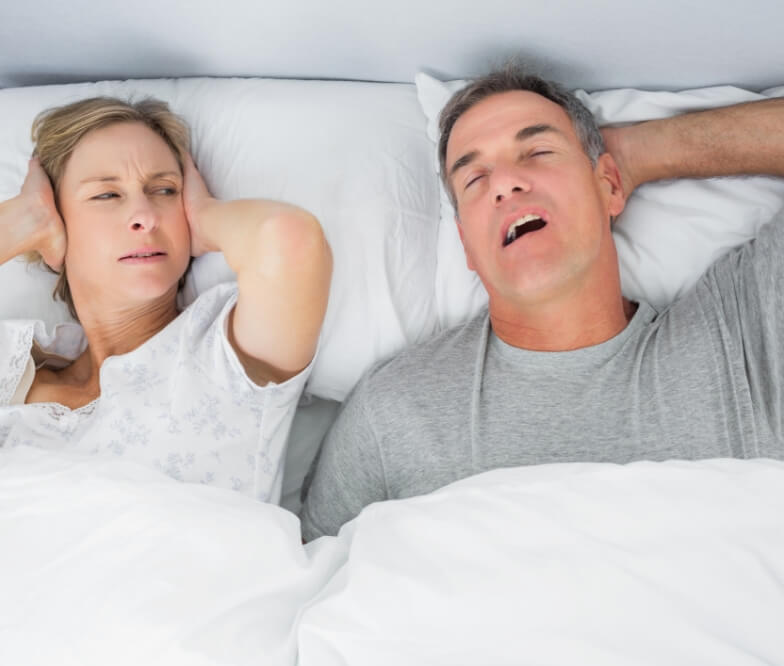 Frustrated woman next to snoring man in need of sleep apnea therapy